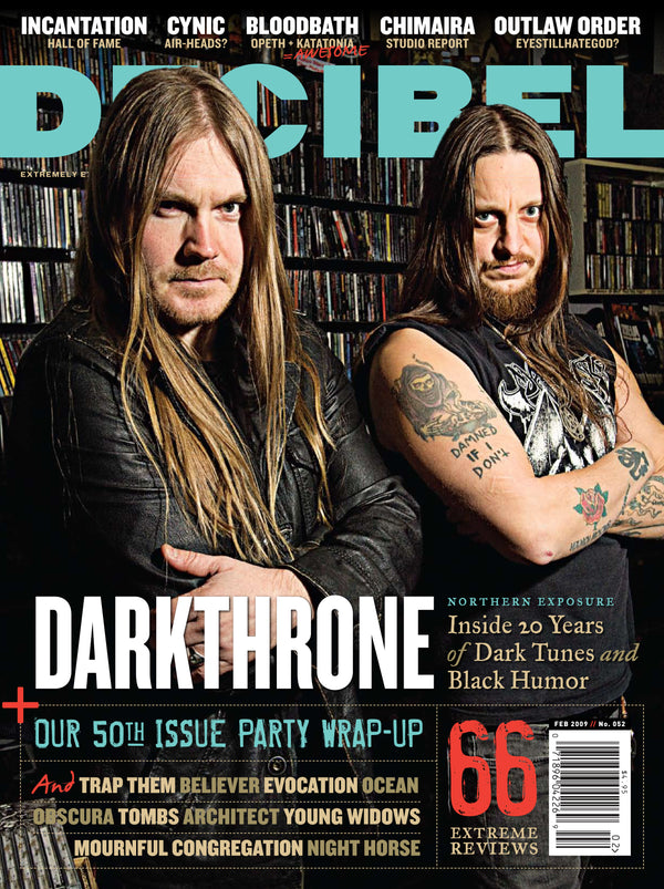 Magazine cover featuring two individuals with long hair and tattoos, set against a bookshelf background.